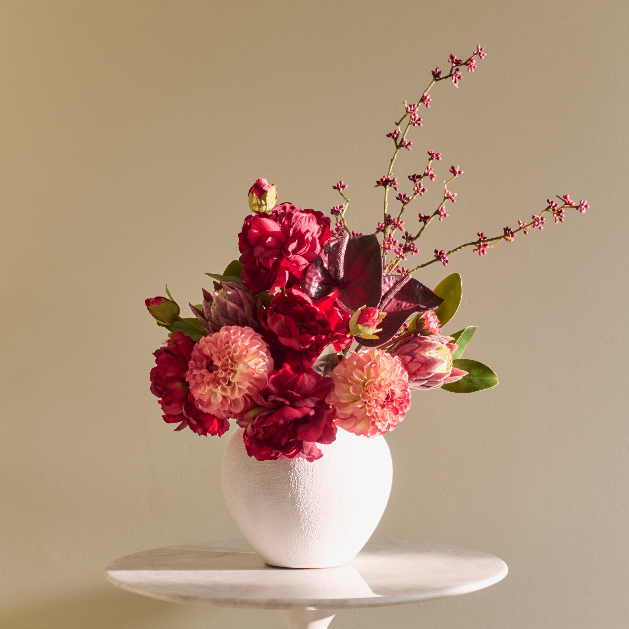 Floral arrangement in a white vase on a beige background