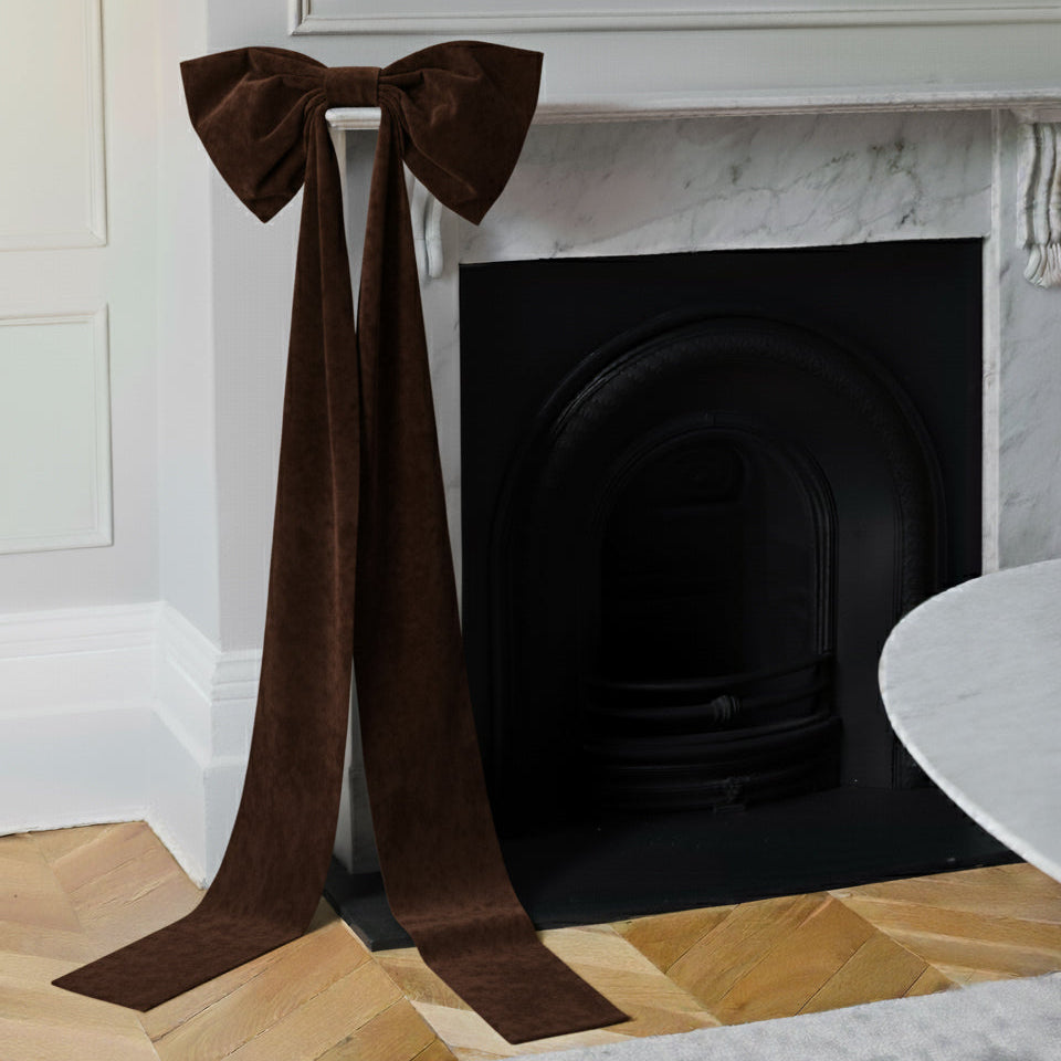 Brown velvet bow decoration on a fireplace mantel.