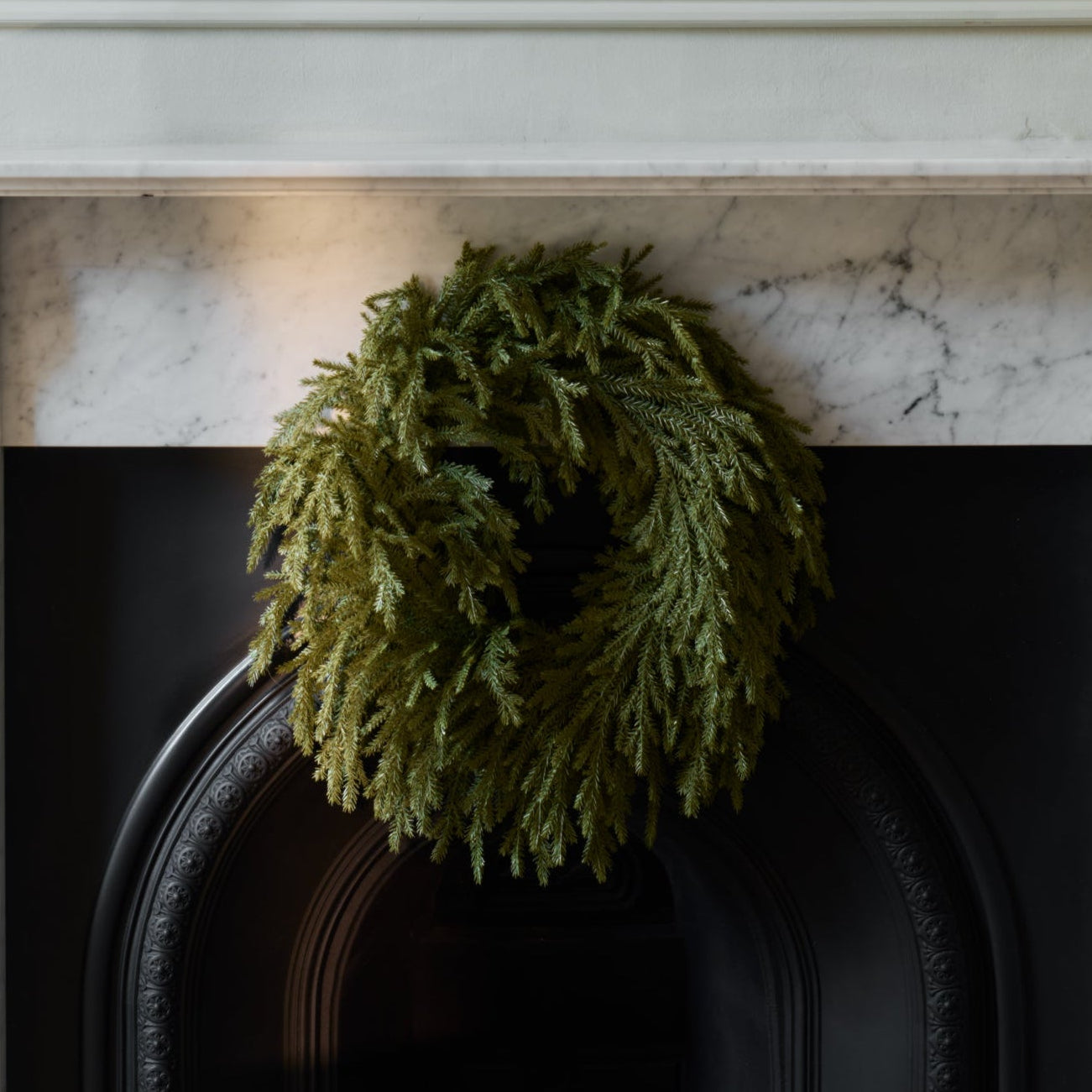 Green wreath on a fireplace mantel