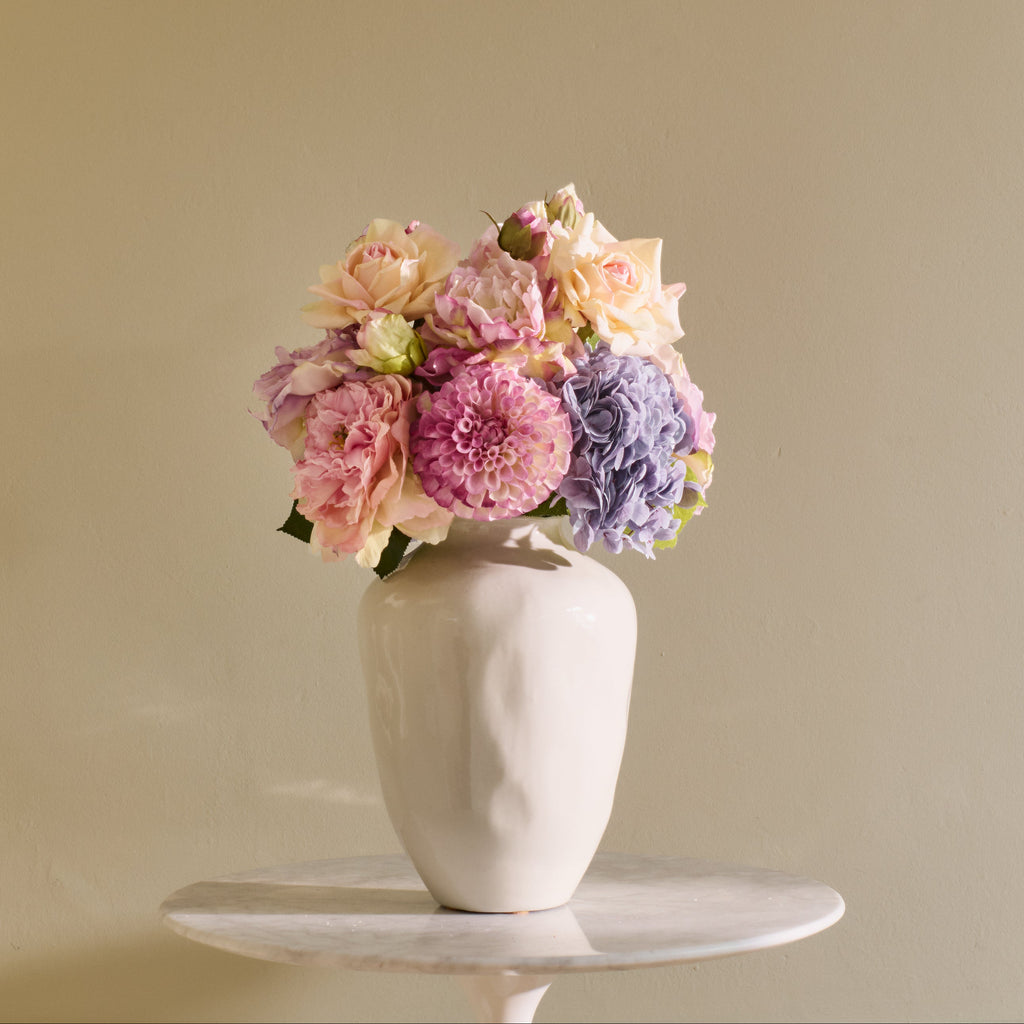 White vase with pastel flowers on a beige background
