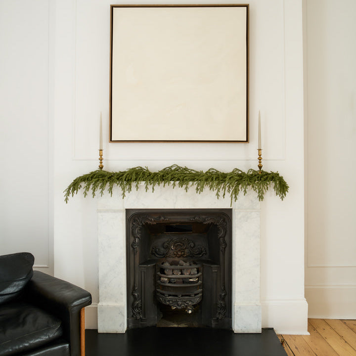 Living room with a fireplace decorated with greenery and a framed picture above.