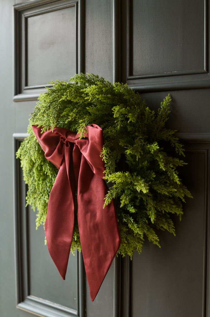 Green wreath with a red ribbon on a dark gray door