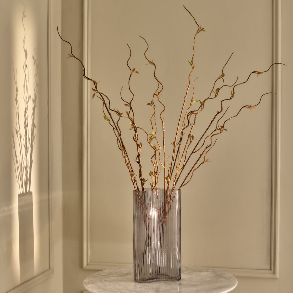 Decorative glass vase with wavy branches on a neutral background