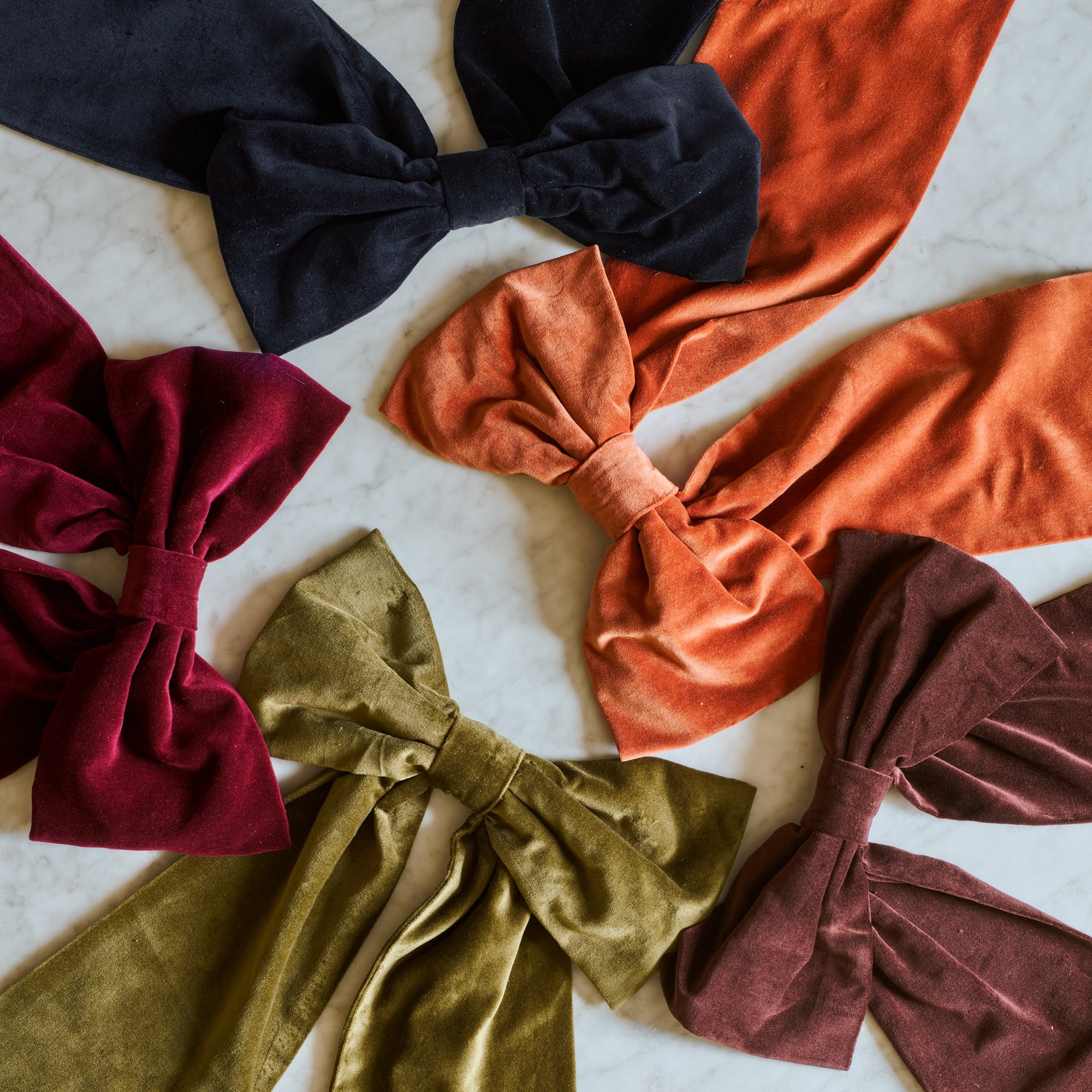 Set of colorful velvet hair bows on a textured surface