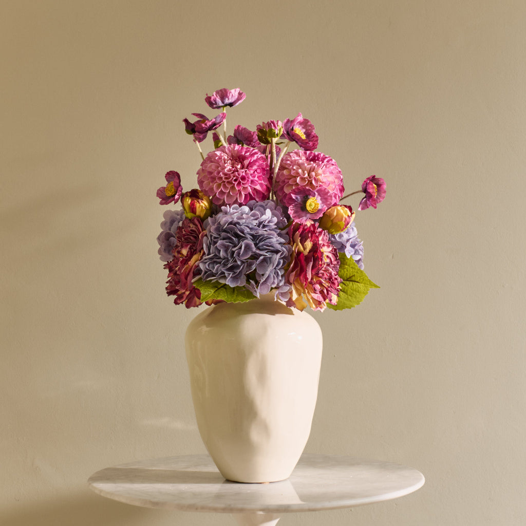 Vase with colorful flowers on a beige background
